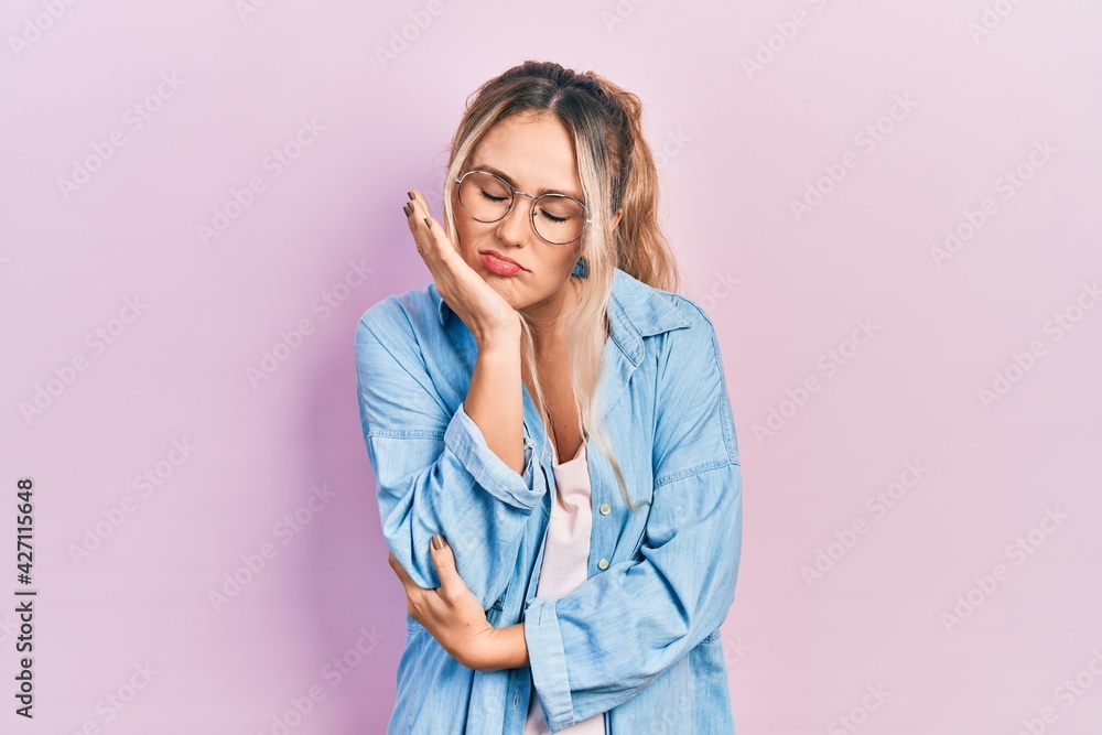 Beautiful young blonde woman wearing casual clothes and glasses thinking looking tired and bored with depression problems with crossed arms. Beautiful young blonde woman wearing casual clothes and glasses thinking looking tired and bored with depression problems with crossed arms.