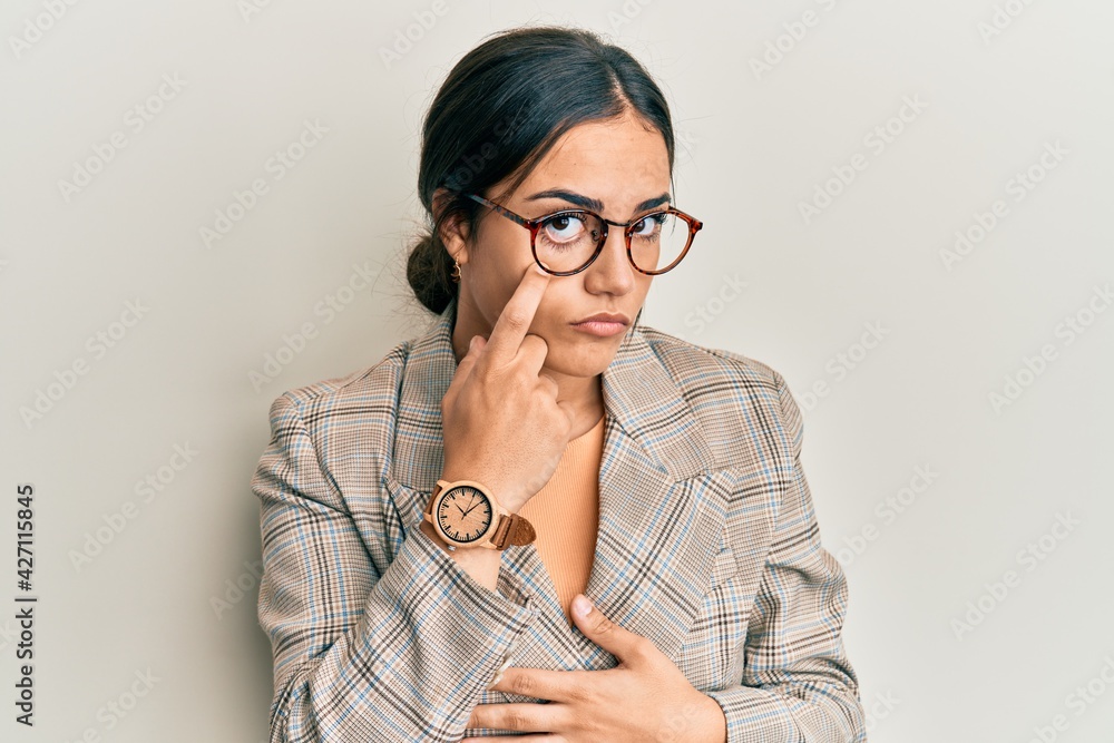 Young brunette woman wearing business jacket and glasses pointing to the eye watching you gesture, suspicious expression