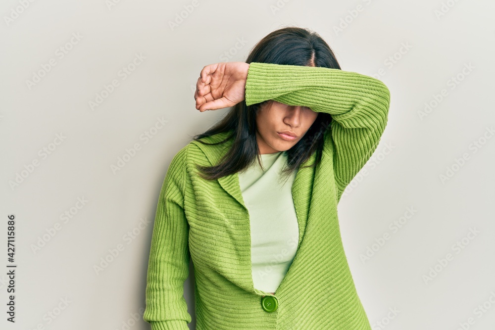 Young brunette woman wearing casual clothes covering eyes with arm, looking serious and sad. sightless, hiding and rejection concept Young brunette woman wearing casual clothes covering eyes with arm, looking serious and sad. sightless, hiding and rejection concept