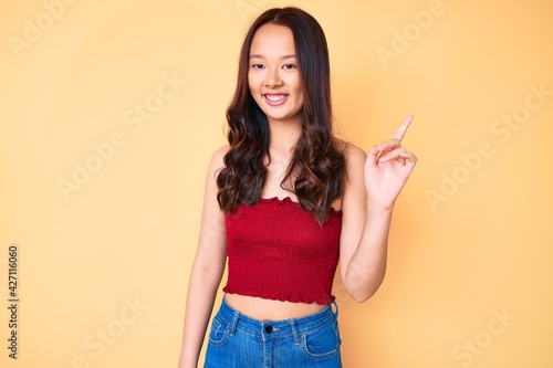 Young beautiful chinese girl wearing summer clothes smiling happy pointing with hand and finger to the side