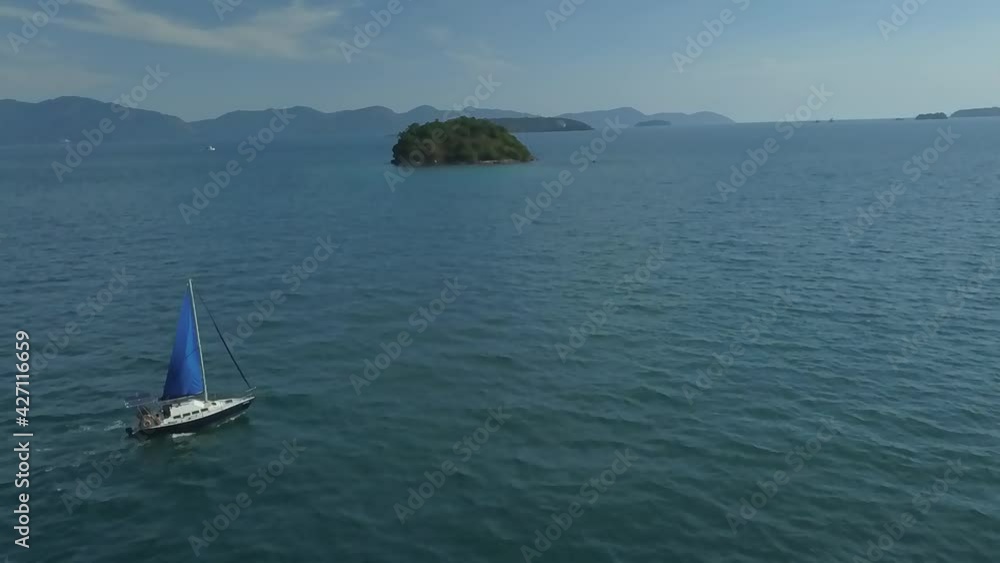 Aerial and slow motion view of a sailboat sailing in the limpid waters of the bay of Angra dos Reis, Rio de Janeiro, Brazil Aerial and slow motion view of a sailboat sailing in the limpid waters of the bay of Angra dos Reis, Rio de Janeiro, Brazil