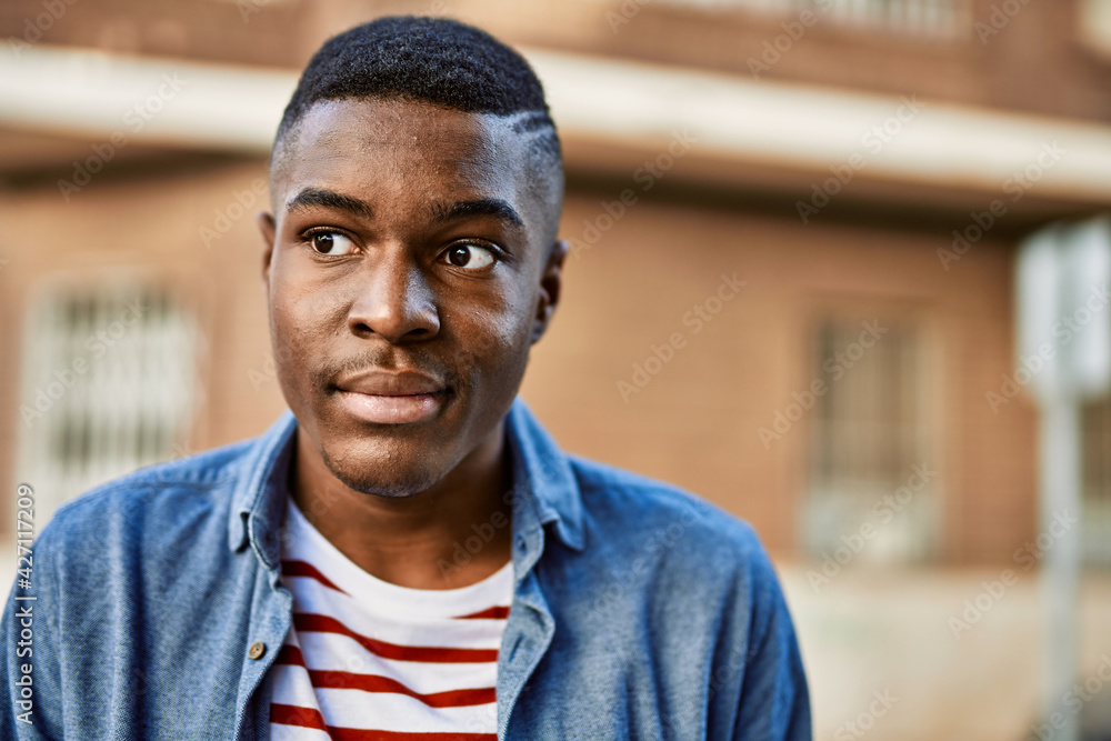 Young african american man with relaxed expression standing at the city. Young african american man with relaxed expression standing at the city.