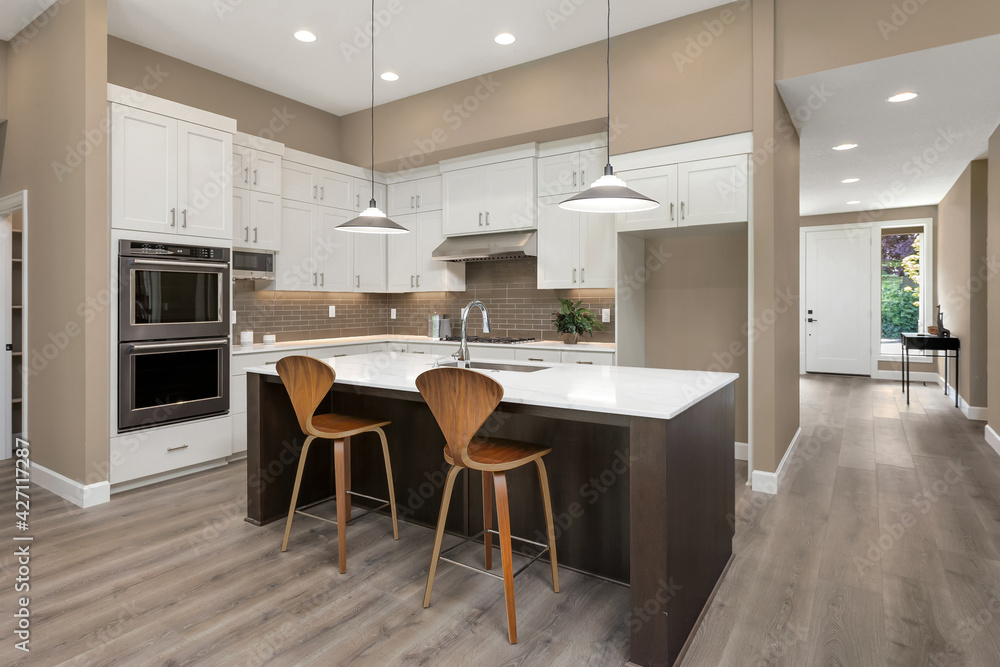 Beautiful kitchen in new luxury home with large island, pendant lights, and stainless steel appliances
