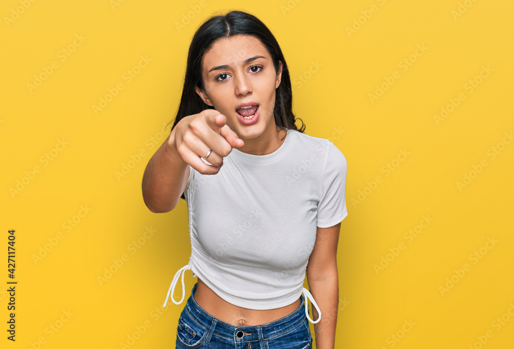 Young hispanic girl wearing casual white t shirt pointing displeased and frustrated to the camera, angry and furious with you Young hispanic girl wearing casual white t shirt pointing displeased and frustrated to the camera, angry and furious with you