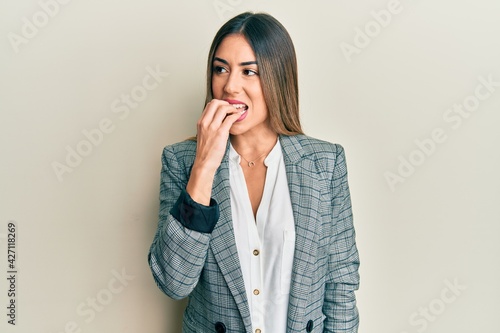 Young hispanic woman wearing business clothes looking stressed and nervous with hands on mouth biting nails. anxiety problem.