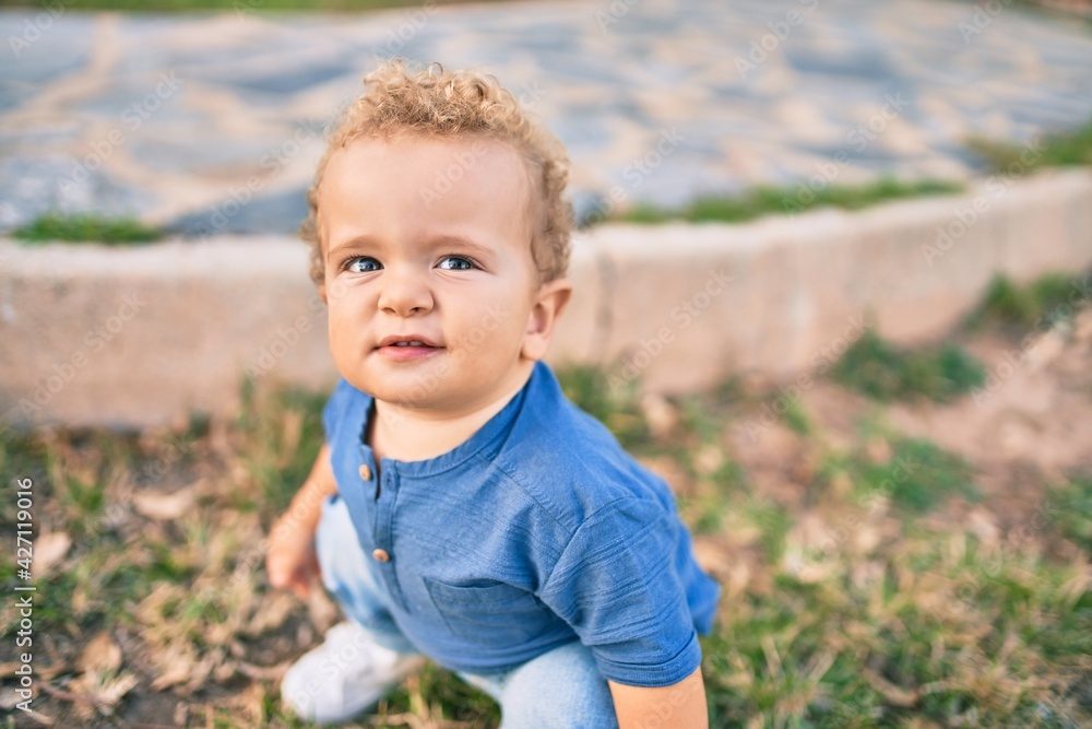 Cute and happy little boy having fun at the park on a sunny day. Beautiful blonde hair male toddler playing outdoors Cute and happy little boy having fun at the park on a sunny day. Beautiful blonde hair male toddler playing outdoors