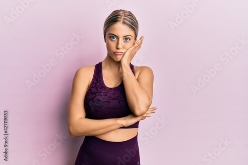 Beautiful blonde woman wearing sportswear over pink background thinking looking tired and bored with depression problems with crossed arms.