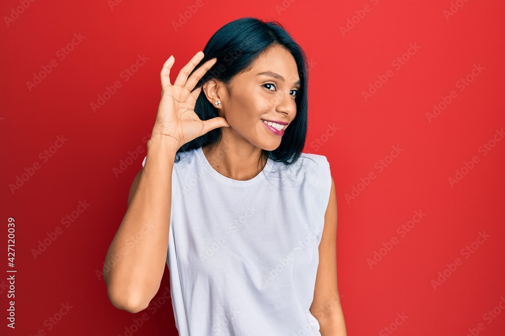 Fototapeta premium Young african american woman wearing casual clothes smiling with hand over ear listening and hearing to rumor or gossip. deafness concept.