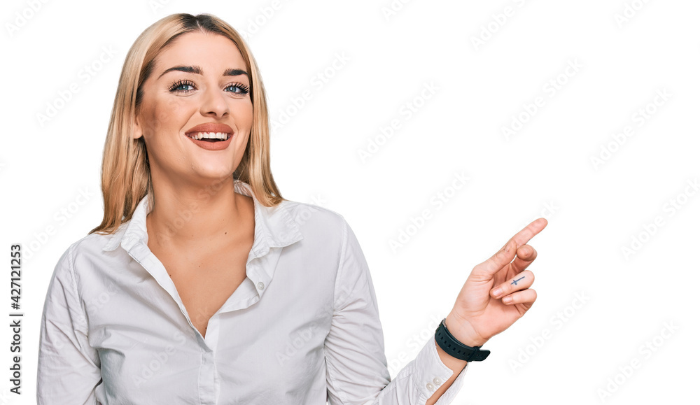 Young caucasian woman wearing casual clothes with a big smile on face, pointing with hand finger to the side looking at the camera. Young caucasian woman wearing casual clothes with a big smile on face, pointing with hand finger to the side looking at the camera.