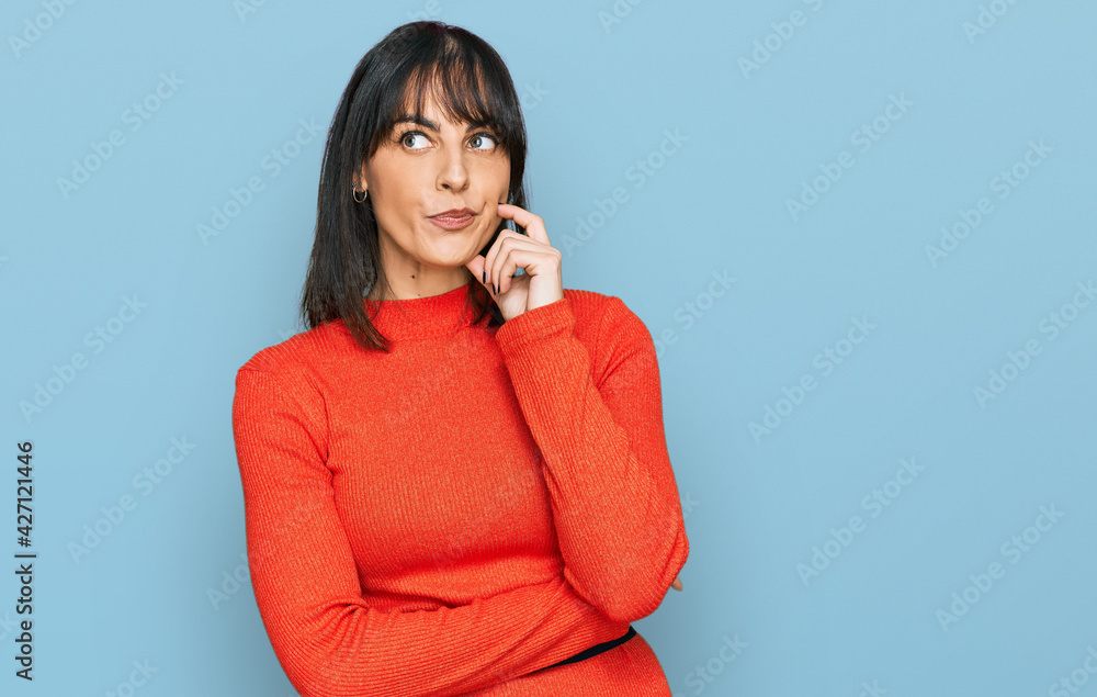Young hispanic woman wearing casual clothes serious face thinking about question with hand on chin, thoughtful about confusing idea Young hispanic woman wearing casual clothes serious face thinking about question with hand on chin, thoughtful about confusing idea