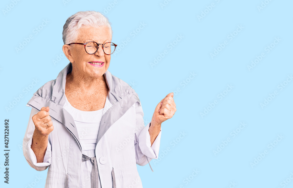 Senior beautiful woman with blue eyes and grey hair wearing casual clothes and glasses excited for success with arms raised and eyes closed celebrating victory smiling. winner concept. Senior beautiful woman with blue eyes and grey hair wearing casual clothes and glasses excited for success with arms raised and eyes closed celebrating victory smiling. winner concept.