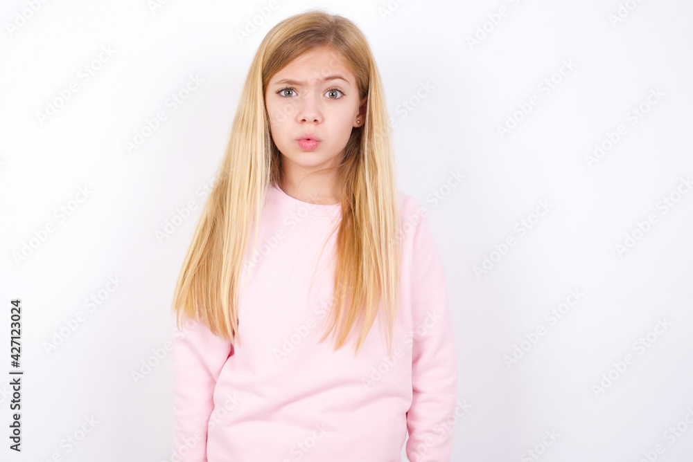 beautiful caucasian little girl wearing pink hoodie over white background expressing disgust, unwillingness, disregard having tensive look frowning face, looking indignant with something. beautiful caucasian little girl wearing pink hoodie over white background expressing disgust, unwillingness, disregard having tensive look frowning face, looking indignant with something.