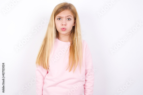 beautiful caucasian little girl wearing pink hoodie over white background expressing disgust  unwillingness  disregard having tensive look frowning face  looking indignant with something.