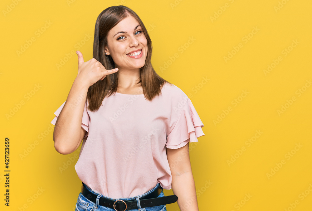Beautiful caucasian woman wearing casual clothes smiling doing phone gesture with hand and fingers like talking on the telephone. communicating concepts. Beautiful caucasian woman wearing casual clothes smiling doing phone gesture with hand and fingers like talking on the telephone. communicating concepts.