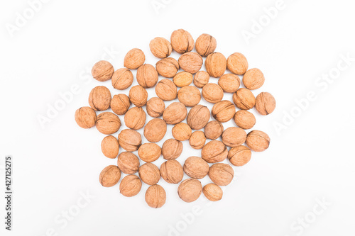 Heap of whole walnuts in the shell isolated on white background