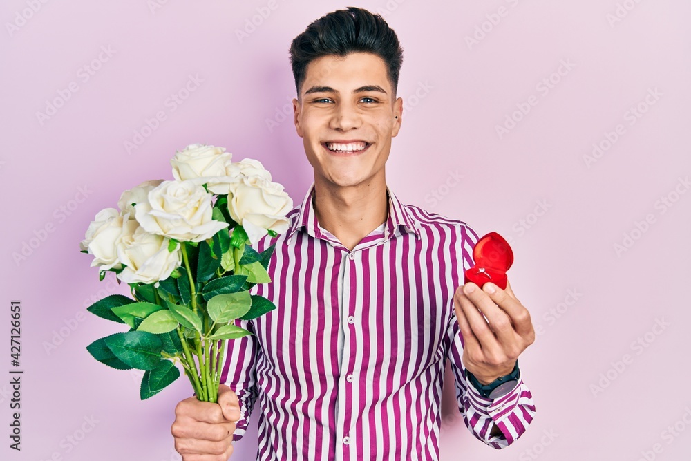 Young hispanic man holding bouquet of flowers and wedding ring smiling with a happy and cool smile on face. showing teeth. Young hispanic man holding bouquet of flowers and wedding ring smiling with a happy and cool smile on face. showing teeth.