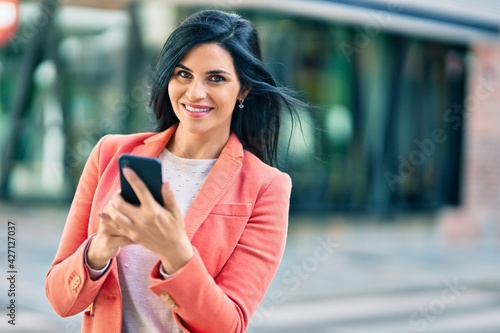 Young beautiful businesswoman smiling happy using smartphone at the city.