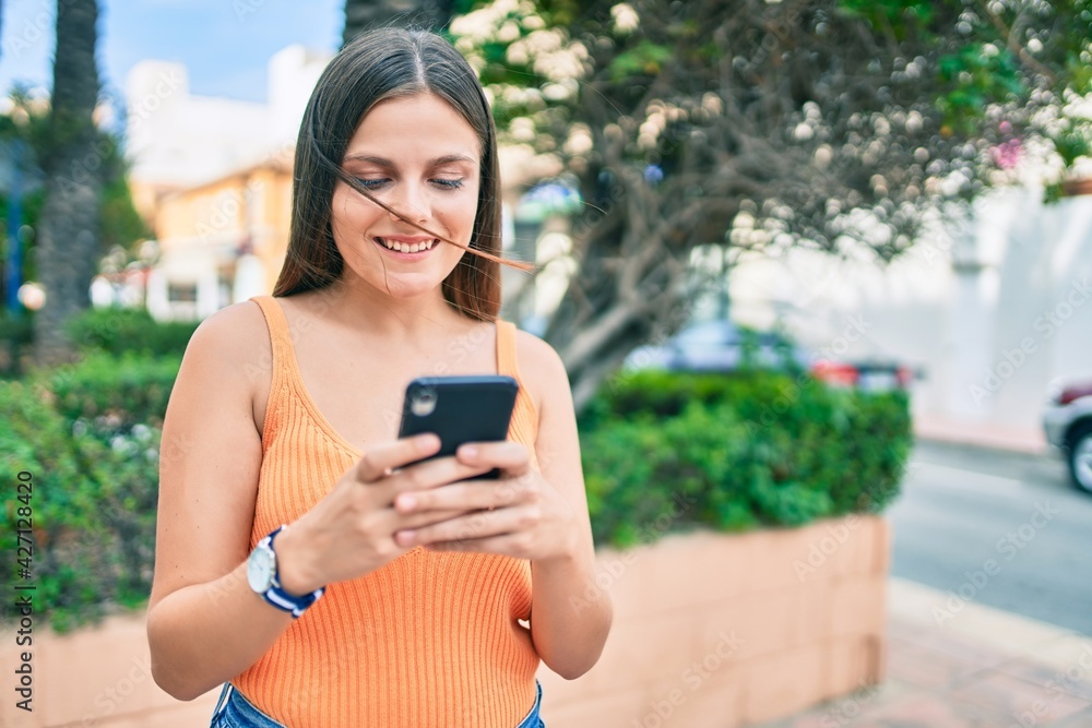 Young middle east girl smiling happy using smartphone at the city. Young middle east girl smiling happy using smartphone at the city.