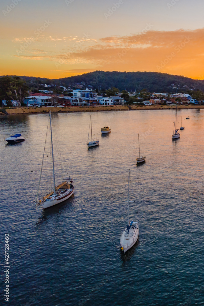 Obraz premium Aerial sunrise waterscape over the channel with orange clouds and boats below