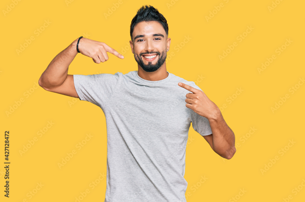 Young man with beard wearing casual grey tshirt smiling cheerful showing and pointing with fingers teeth and mouth. dental health concept. Young man with beard wearing casual grey tshirt smiling cheerful showing and pointing with fingers teeth and mouth. dental health concept.
