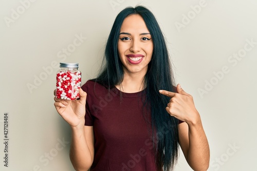 Young hispanic girl holding pills pointing finger to one self smiling happy and proud © Krakenimages.com