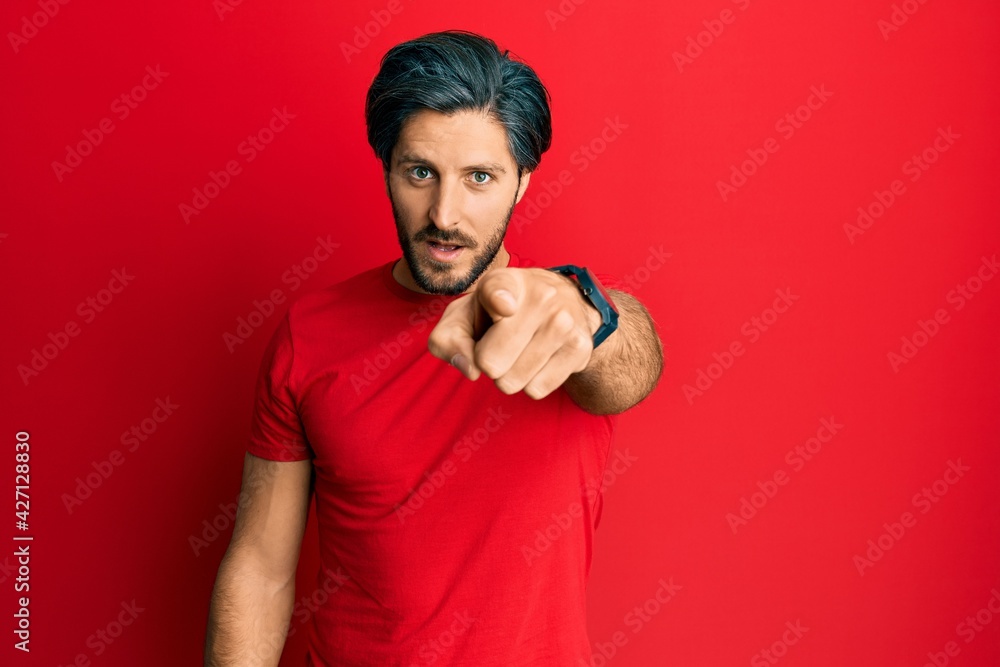 Young hispanic man wearing casual red t shirt pointing displeased and frustrated to the camera, angry and furious with you Young hispanic man wearing casual red t shirt pointing displeased and frustrated to the camera, angry and furious with you