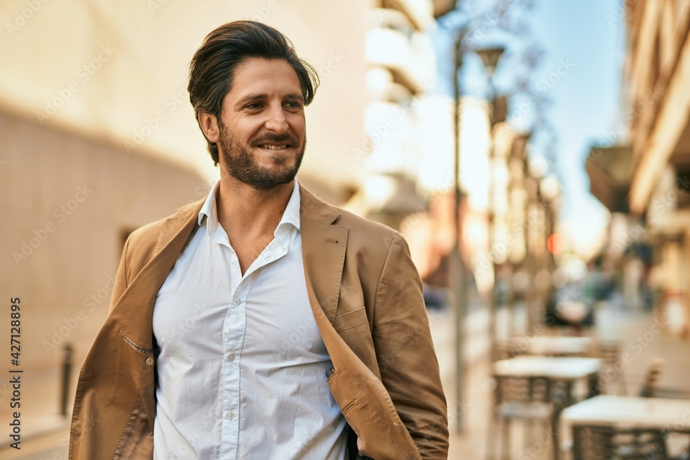 Obraz premium Young hispanic businessman smiling happy standing at the city.