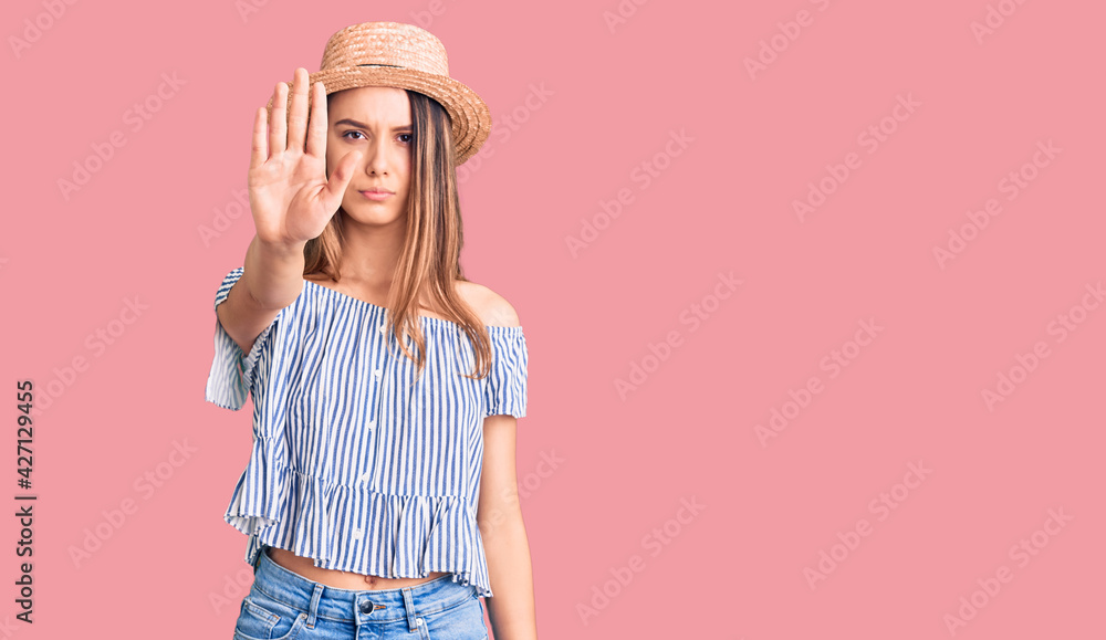 Young beautiful girl wearing hat and t shirt doing stop sing with palm of the hand. warning expression with negative and serious gesture on the face. Young beautiful girl wearing hat and t shirt doing stop sing with palm of the hand. warning expression with negative and serious gesture on the face.