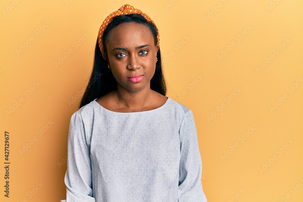 Young african woman wearing casual clothes over yellow background with serious expression on face. simple and natural looking at the camera. Young african woman wearing casual clothes over yellow background with serious expression on face. simple and natural looking at the camera.
