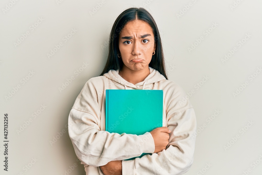 Young asian woman holding book depressed and worry for distress, crying angry and afraid. sad expression. Young asian woman holding book depressed and worry for distress, crying angry and afraid. sad expression.