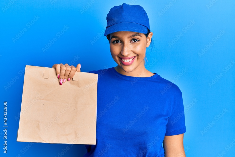 Beautiful brunette woman holding take away paper bag looking positive and happy standing and smiling with a confident smile showing teeth Beautiful brunette woman holding take away paper bag looking positive and happy standing and smiling with a confident smile showing teeth