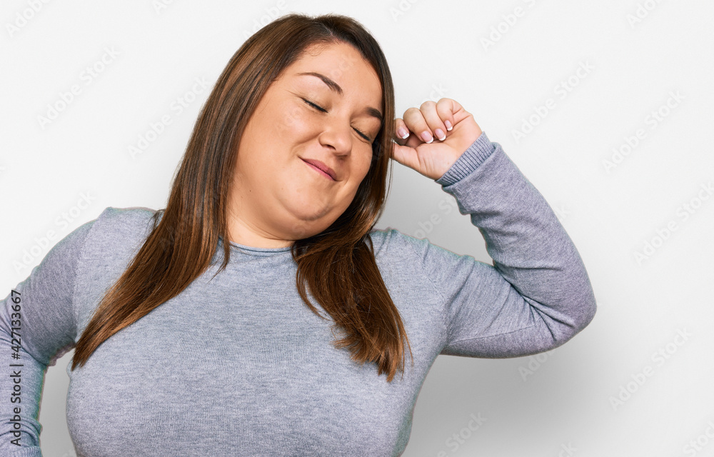 Beautiful brunette plus size woman wearing casual clothes stretching back, tired and relaxed, sleepy and yawning for early morning Beautiful brunette plus size woman wearing casual clothes stretching back, tired and relaxed, sleepy and yawning for early morning