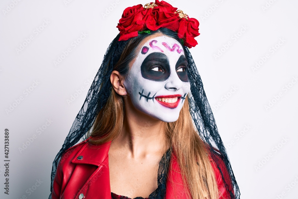 Woman wearing day of the dead costume over white looking away to side with smile on face, natural expression. laughing confident.