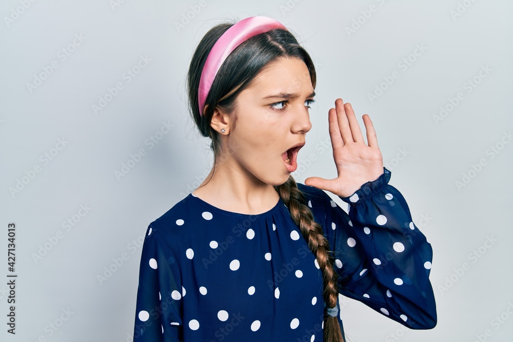 Young brunette girl wearing elegant look shouting and screaming loud to side with hand on mouth. communication concept. Young brunette girl wearing elegant look shouting and screaming loud to side with hand on mouth. communication concept.