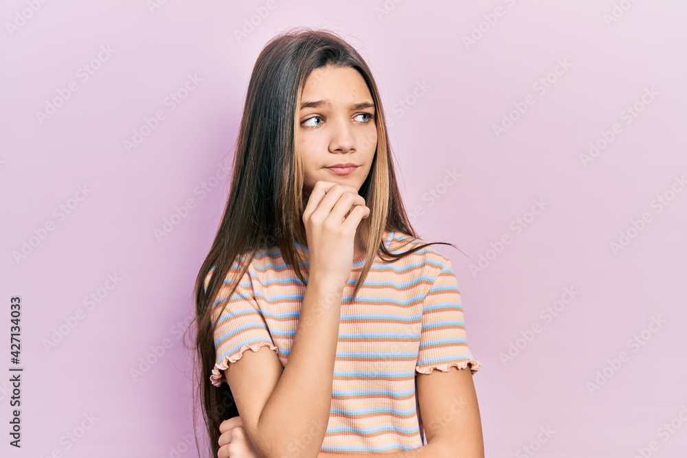 Young brunette girl wearing casual striped t shirt thinking concentrated about doubt with finger on chin and looking up wondering Young brunette girl wearing casual striped t shirt thinking concentrated about doubt with finger on chin and looking up wondering