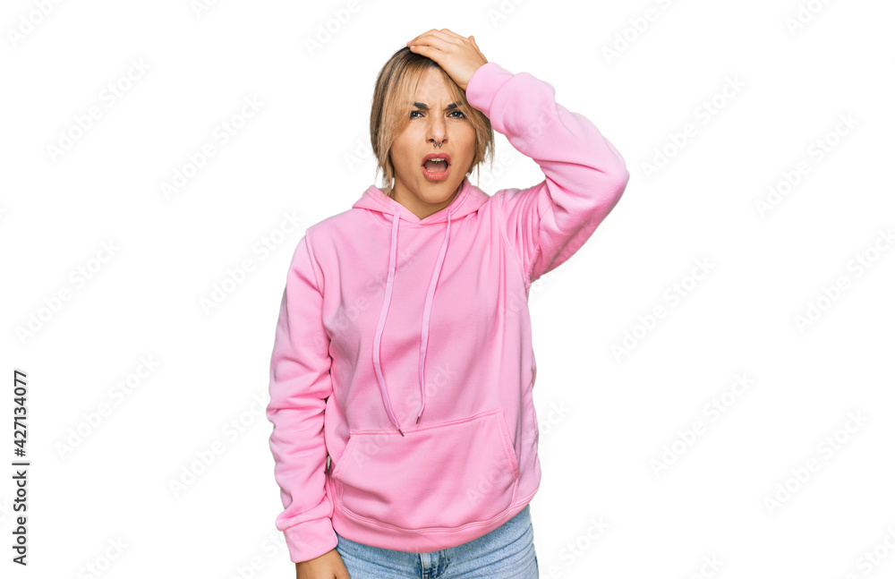 Young caucasian woman wearing casual sweatshirt surprised with hand on head for mistake, remember error. forgot, bad memory concept. Young caucasian woman wearing casual sweatshirt surprised with hand on head for mistake, remember error. forgot, bad memory concept.