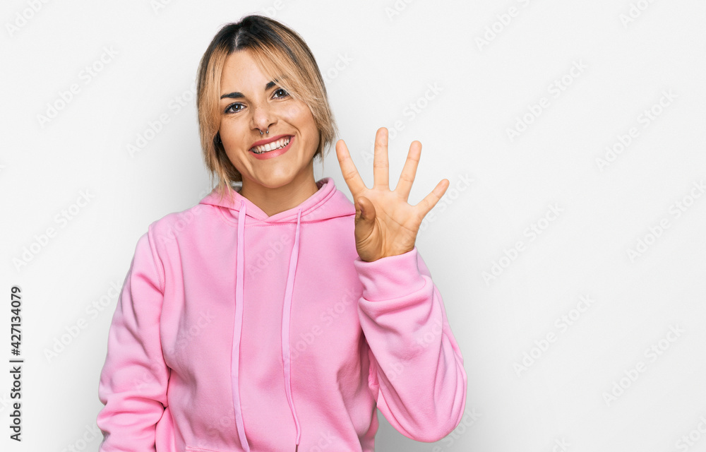 Young caucasian woman wearing casual sweatshirt showing and pointing up with fingers number four while smiling confident and happy. Young caucasian woman wearing casual sweatshirt showing and pointing up with fingers number four while smiling confident and happy.