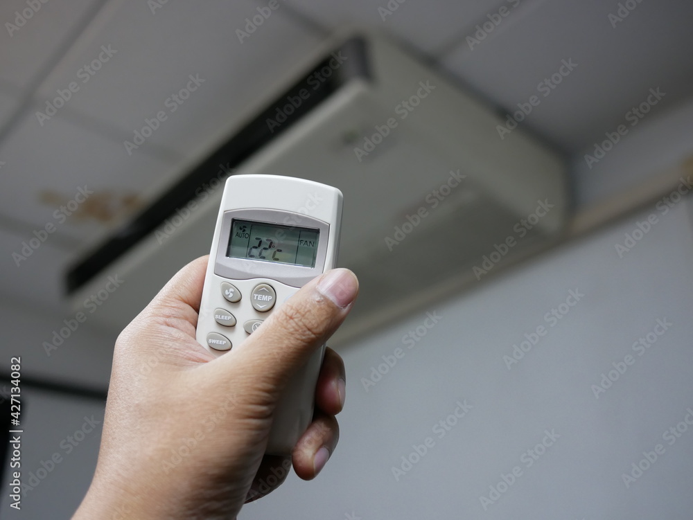 closeup of hand using remote control air conditioner in office. closeup of hand using remote control air conditioner in office.