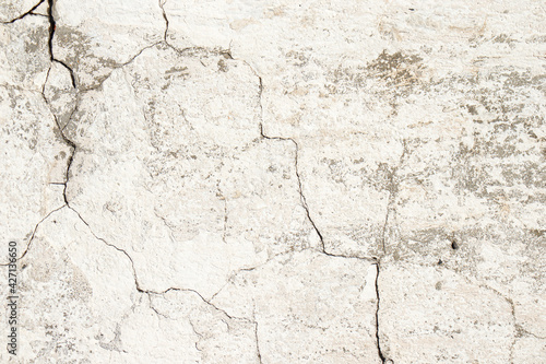 Old cracked cement plaster, whitewashed with white paint. In some places, a gray color is visible.