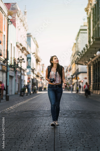 young woman walking in the middle of the street at sunset
