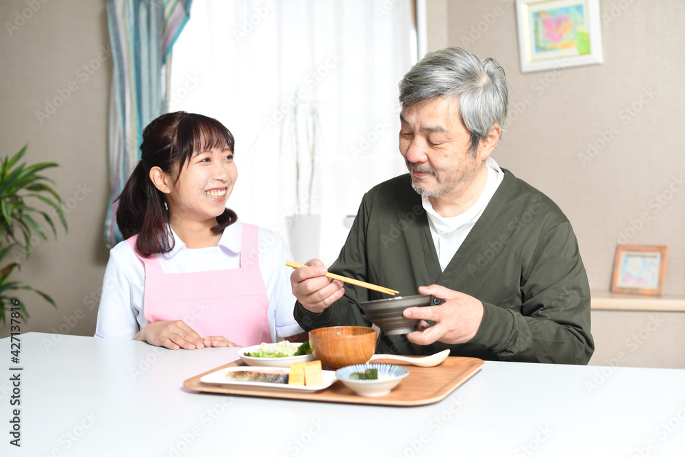 食事をする高齢者男性とエプロン姿の女性介護士