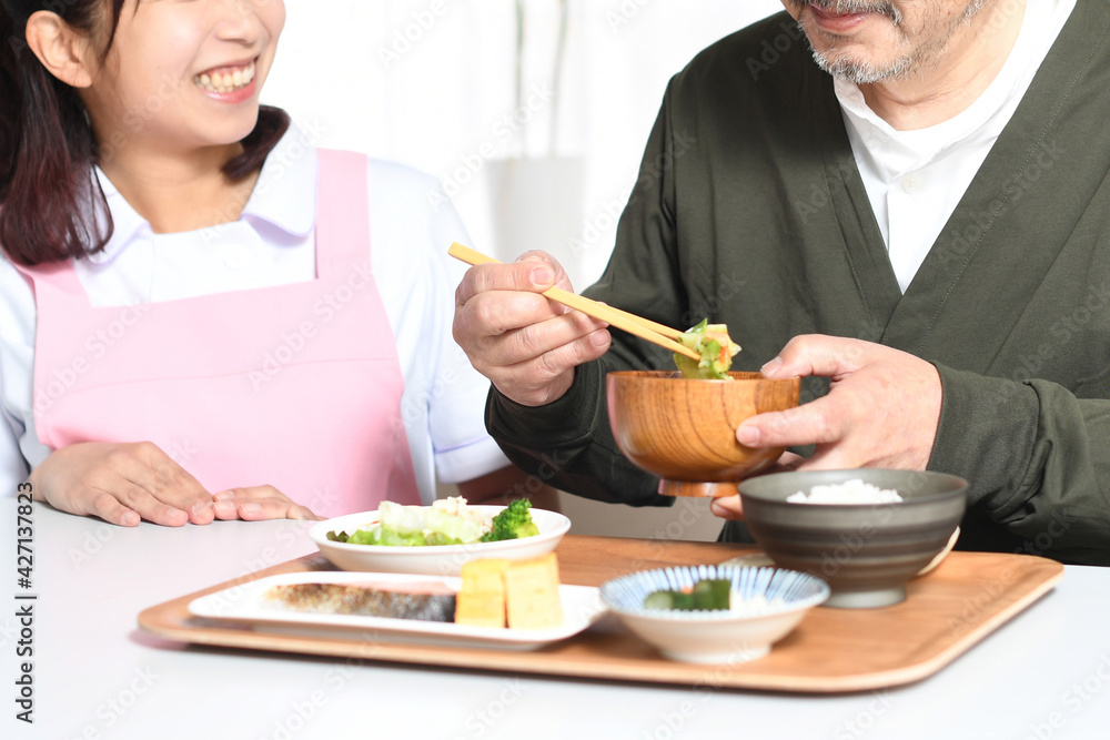 食事をする高齢者男性とエプロン姿の女性介護士
