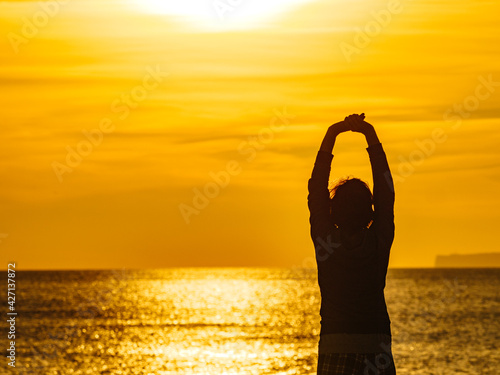 Woman on beach enjoy sunrise with arms up