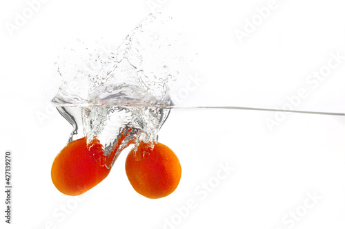 two tangerines falls into the water on a white background, isolate, place under the text