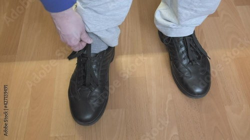 Man is limping, he rubbed his foot with tight shoes. Person takes off his shoes and touches the injured leg. The concept of foot pain due to uncomfortable, improper sized shoes