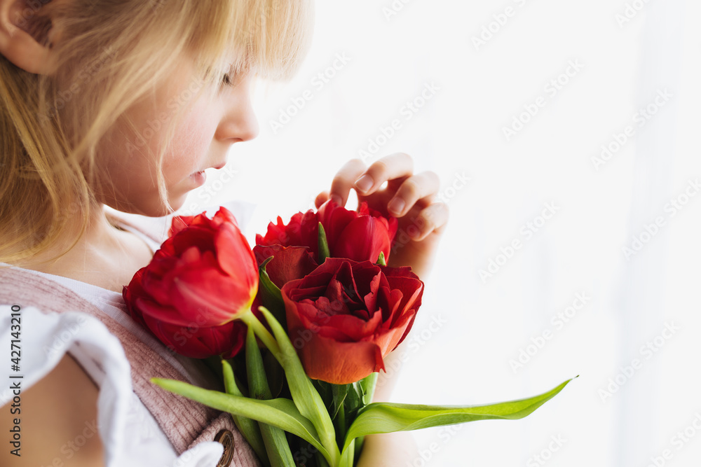Smiling small girl holding bouquet of red tulips. Concept for greeting card Smiling small girl holding bouquet of red tulips. Concept for greeting card