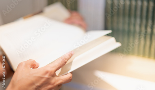 Female hand holding notebook and reading book for relax and the knowledge while sitting on the sofa in the living room in their house.