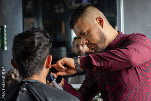 Young Man shaving a customer in a barbershop