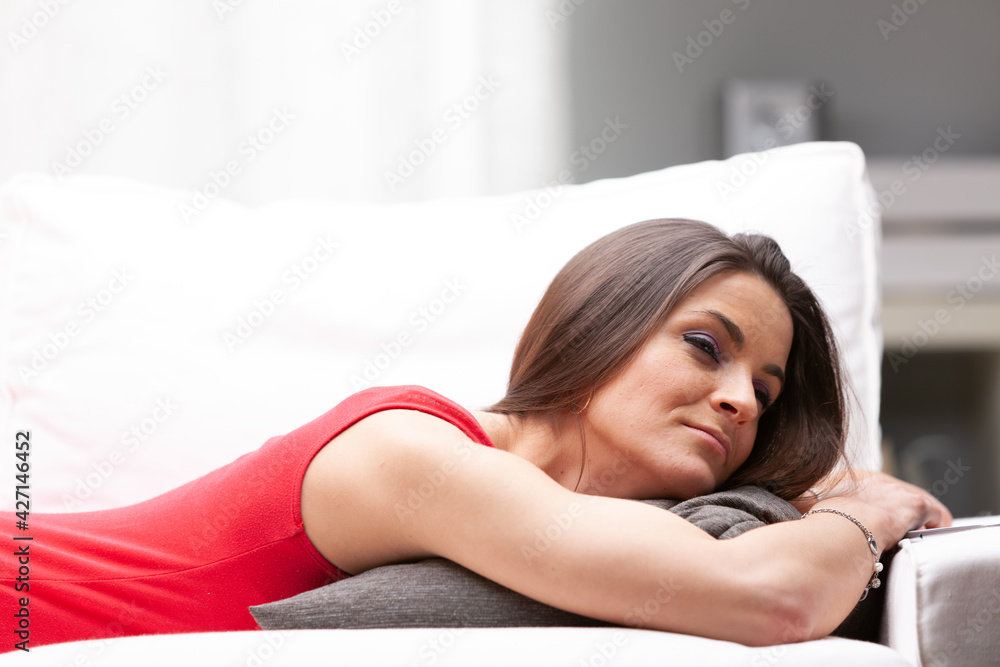 Young woman lying on her stomach relaxing on a sofa Young woman lying on her stomach relaxing on a sofa