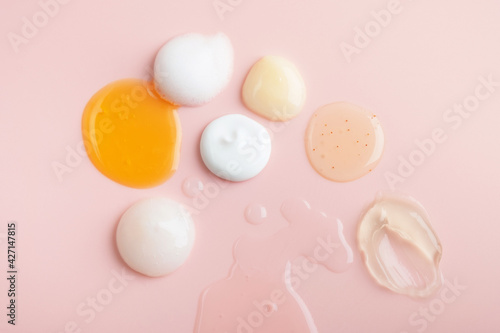 Set of sample cosmetic on pastel pink background. Beauty products for facial and body skincare: moisturizer, serum essence, cleanser foam, tonic, gel aloe vera and balm. Top view photo